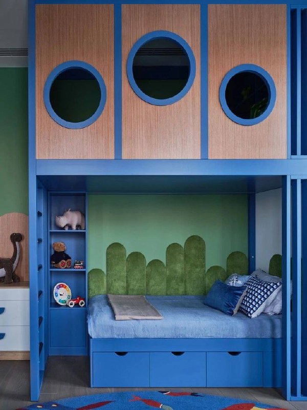 Детская в синей гамме с встроенным нижним спальным местом и практичными ящиками в основании, яркие элементы и текстильные акценты.