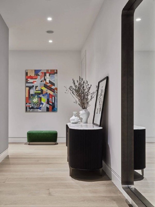 Прихожая с большим зеркалом, консолью и декоративной картиной на стене; нейтральная отделка и функциональная зона входа в квартиру.