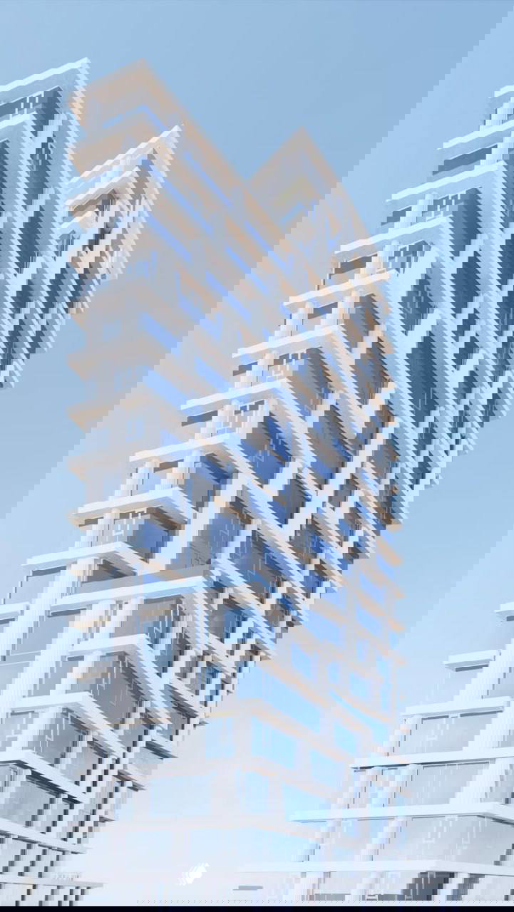 Крупный ракурс фасада проекта: белые горизонтальные пояса, большие окна и террасы в стиле минимализма — ощущение «яхты» и пластики фасада.