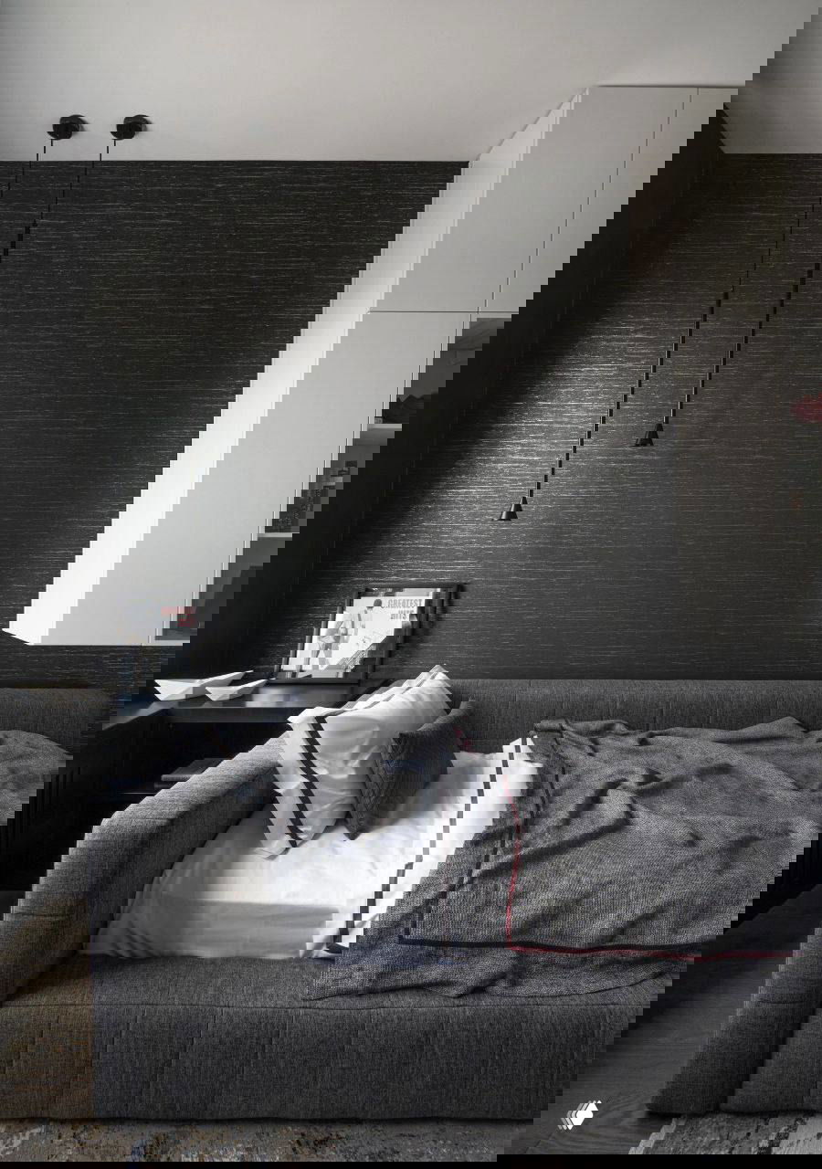 Спальня под скошенным потолком: большая кровать с тёплым пледом и натуральными оттенками, окно с дневным светом создаёт уютную атмосферу в комнате.