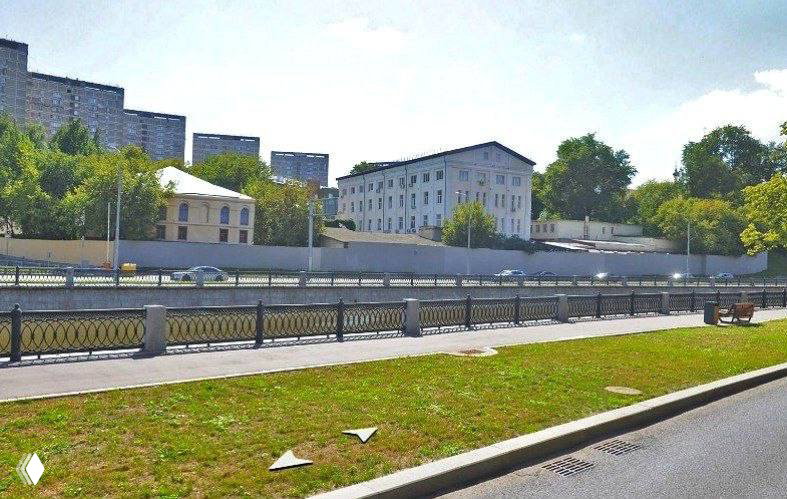 Фотография реальной площадки в Слободском переулке: набережная, ограждение и зелёная полоса рядом с участком под застройку.