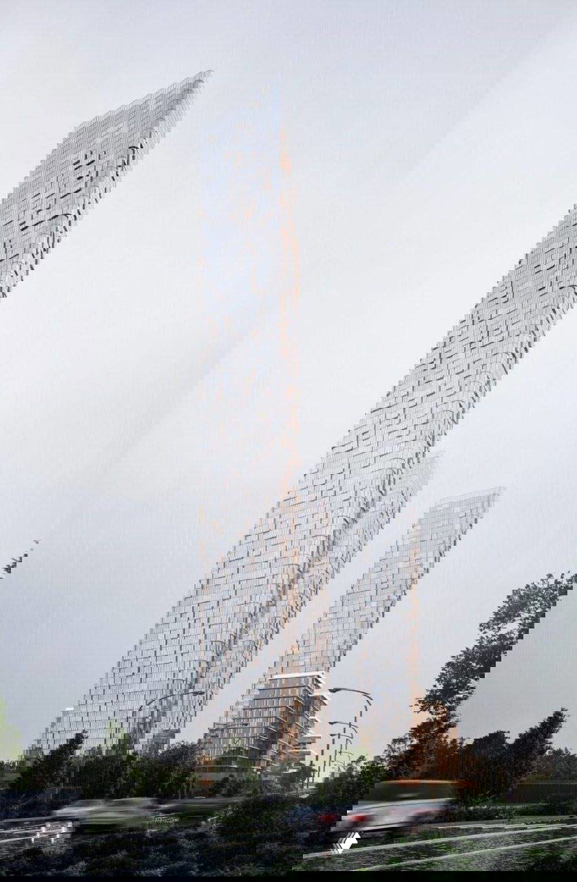 Высотные башни в дождливую погоду: крупный план призмовидных форм с закруглёнными углами и ритмом фасадных панелей.