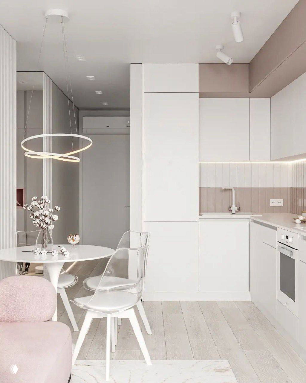 Угол кухни-столовой в 36 м²: встроенные шкафы до потолка, мягкие бежевые акценты и прозрачные стулья рядом с круглым столом.