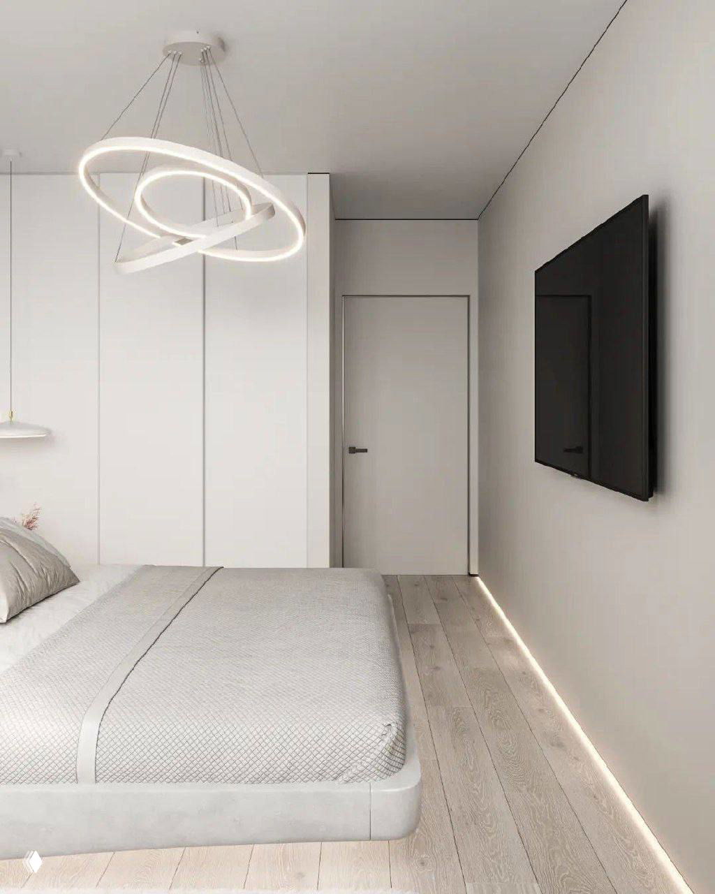 Спальня в компактной квартире 36 м²: низкая кровать, сдержанная светлая отделка, встроенные шкафы и светодиодная подсветка у плинтуса.