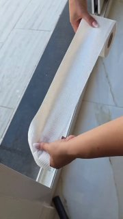 Руки держат свернутую в трубочку тканевую тряпку для чистки порога выхода на балкон; видна часть порога и напольной плитки.