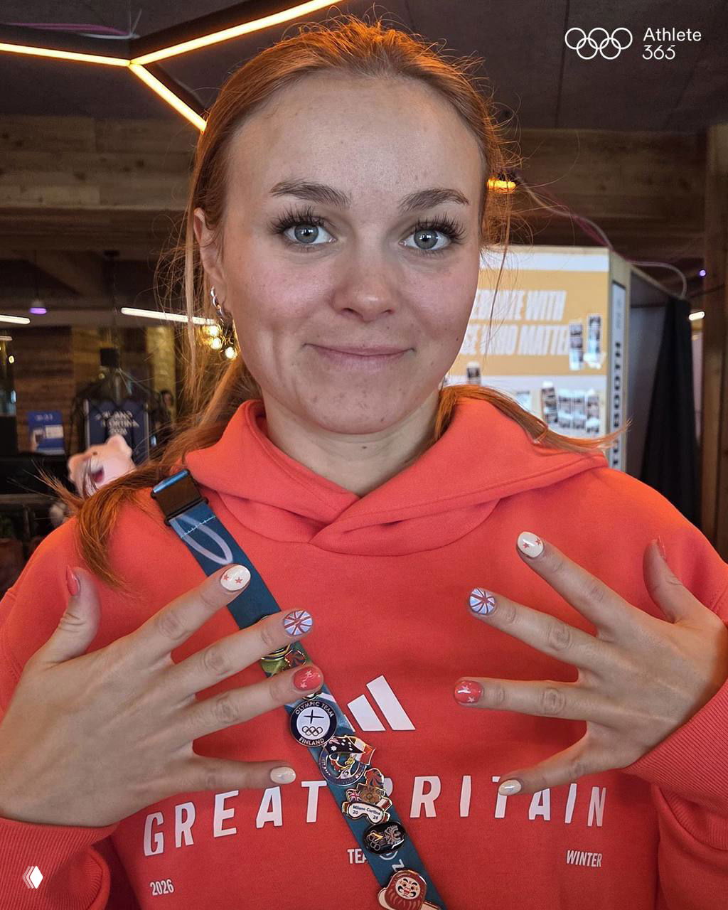 Спортсменка в толстовке Great Britain показывает нежный маникюр с британскими мотивами и аккуратными рисунками на каждом ногте — крупный план рук.