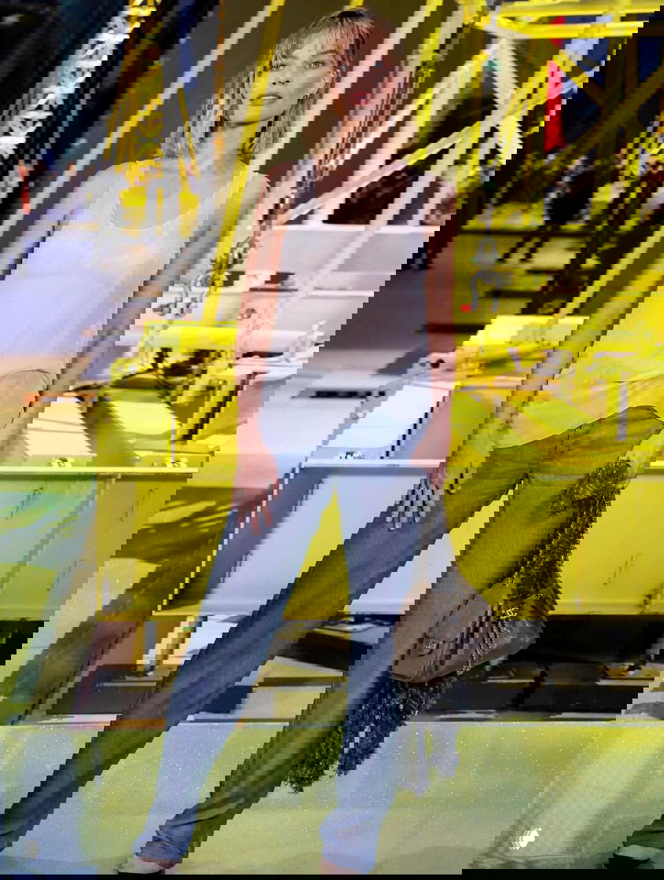 Полноразмерный кадр Марго Робби на показе Chanel: боб чуть выше плеч, прямые джинсы, полупрозрачный топ и сумка в руках на парижской неделе моды.