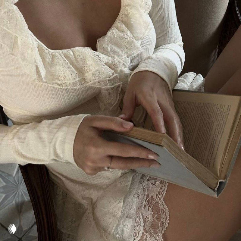 Руки, листающие книгу рядом с кружевной тканью; интимная сцена чтения в ретро-стиле с мягкой фактурой тканей и спокойной атмосферой.