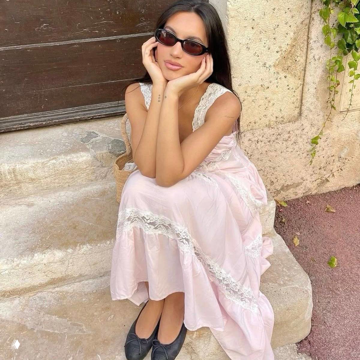 Девушка в светло-розовом платье и тёмных солнцезащитных очках сидит на ступеньке — винтажная, романтичная визуальная история в пастельных тонах.