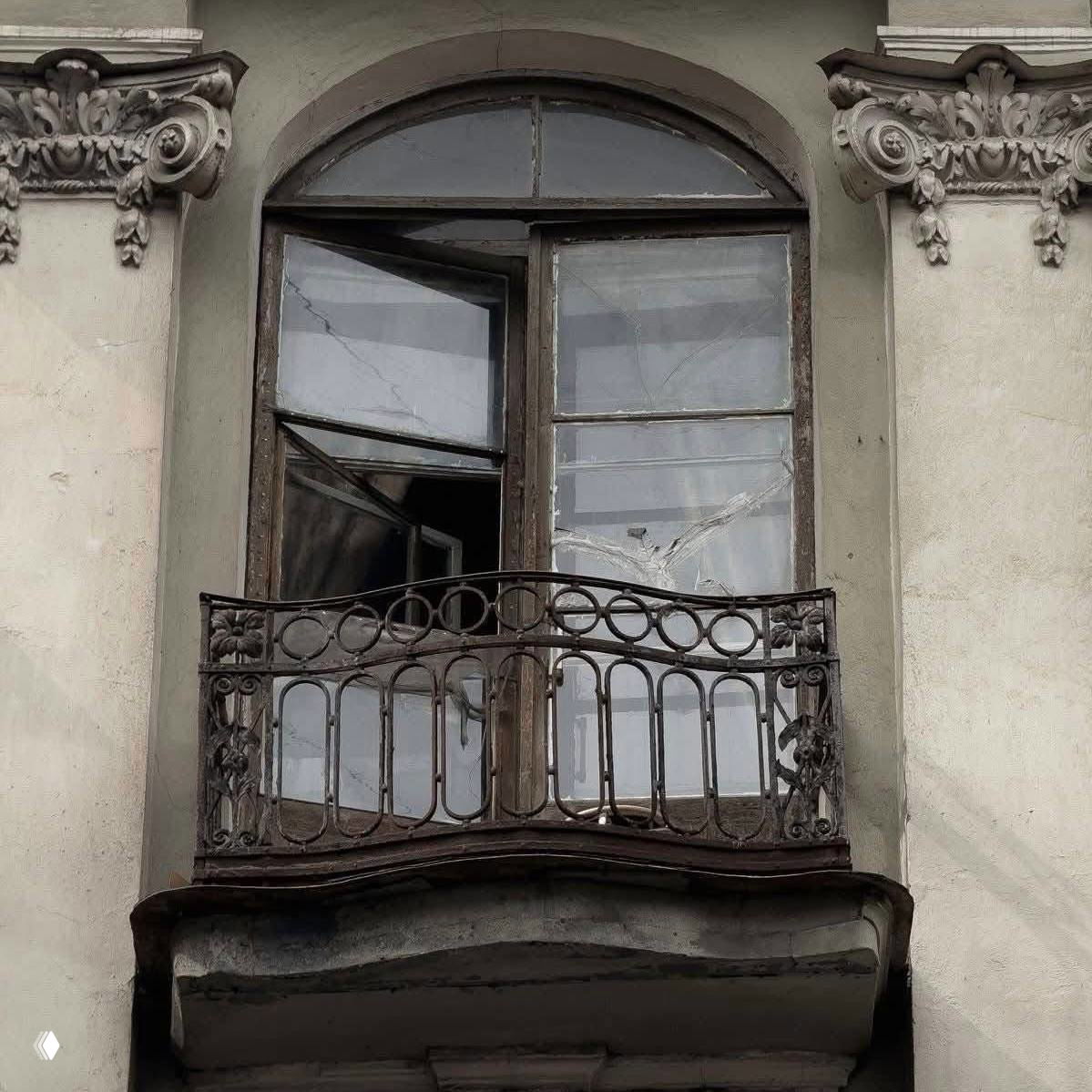 Старая арочная оконная ниша с потрескавшимся стеклом и кованым балконом — винтажная городская архитектура, оттенки времени и патина в духе «Грозовой перевал».