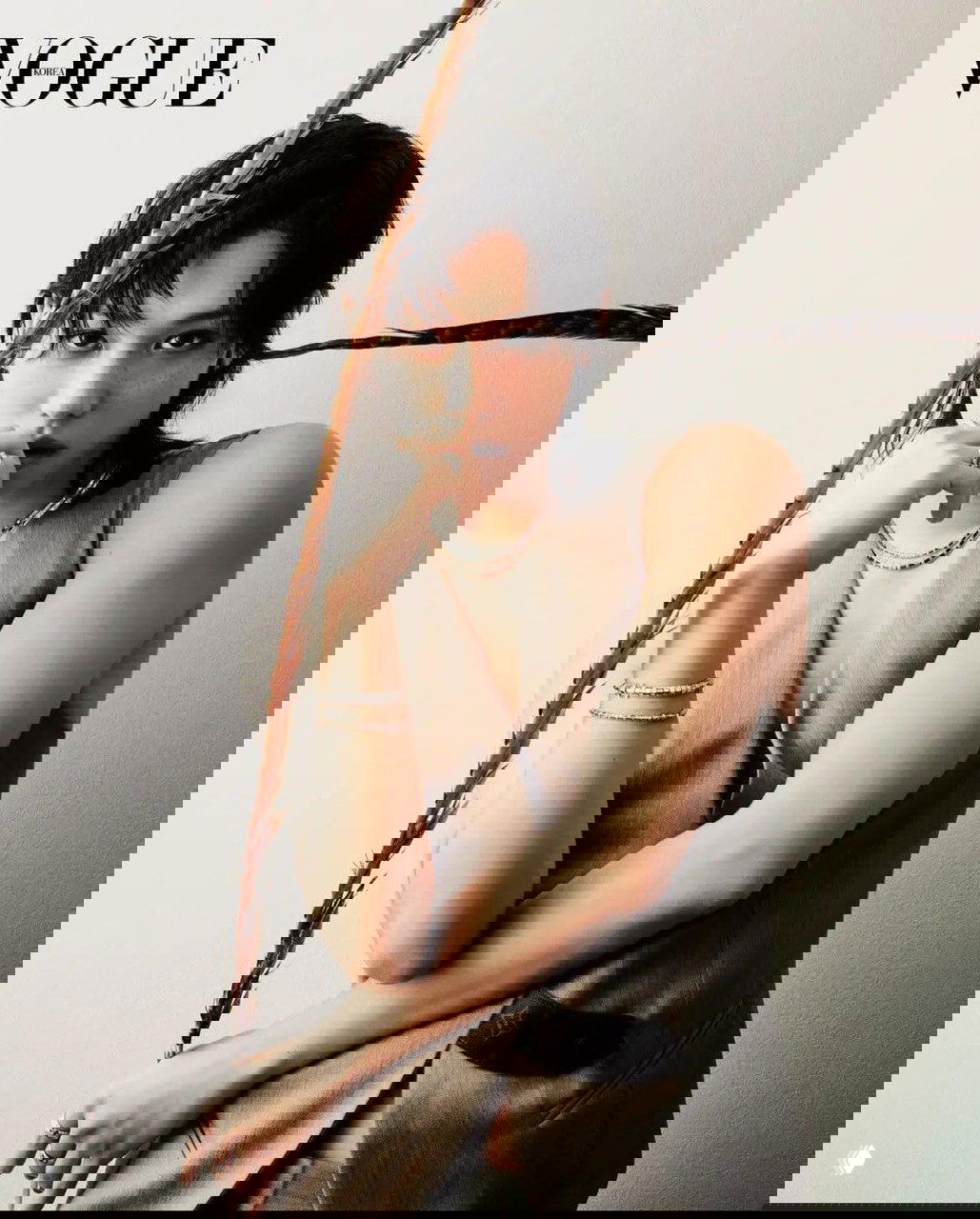 Портрет с декоративной деталью — длинное перо в кадре, строгий взгляд модели и лаконичная стилизация под глянцевую обложку Vogue Korea.