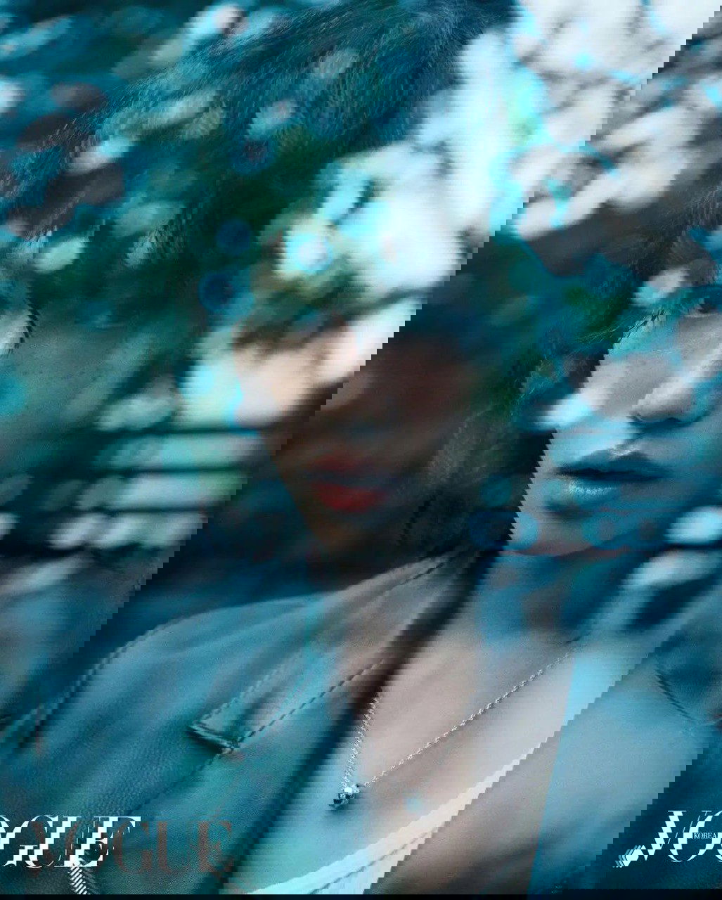 Естественный портрет через стекло с зелеными бликами: модель в расслабленной позе, мягкий фокус и ощущение уюта в кадре.