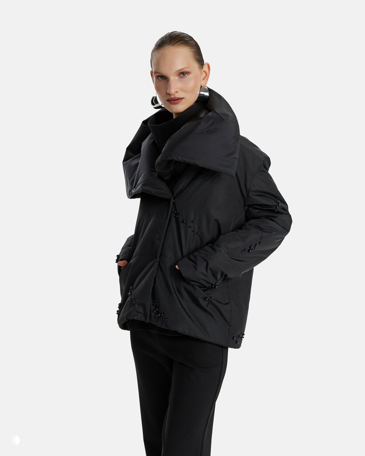Модель в тёплой чёрной стёганой куртке с декоративными элементами на рукаве и карманах, образ подчёркивает объёмный силуэт зимнего дропа LIZURA.