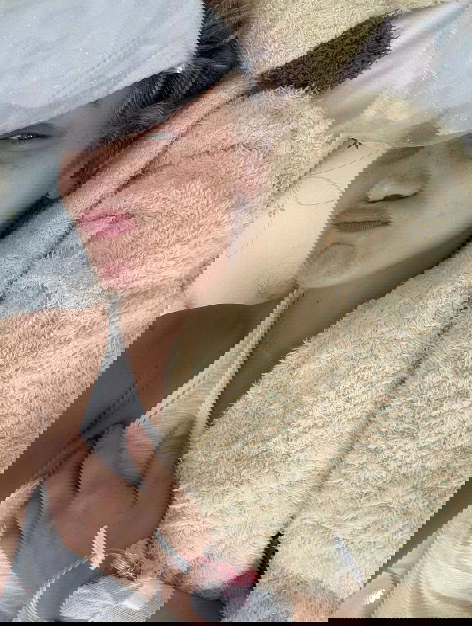 Крупный план модели, лежащей в постели под пледом; на руке видна медицинская капельница — кадр периода восстановления и отдыха