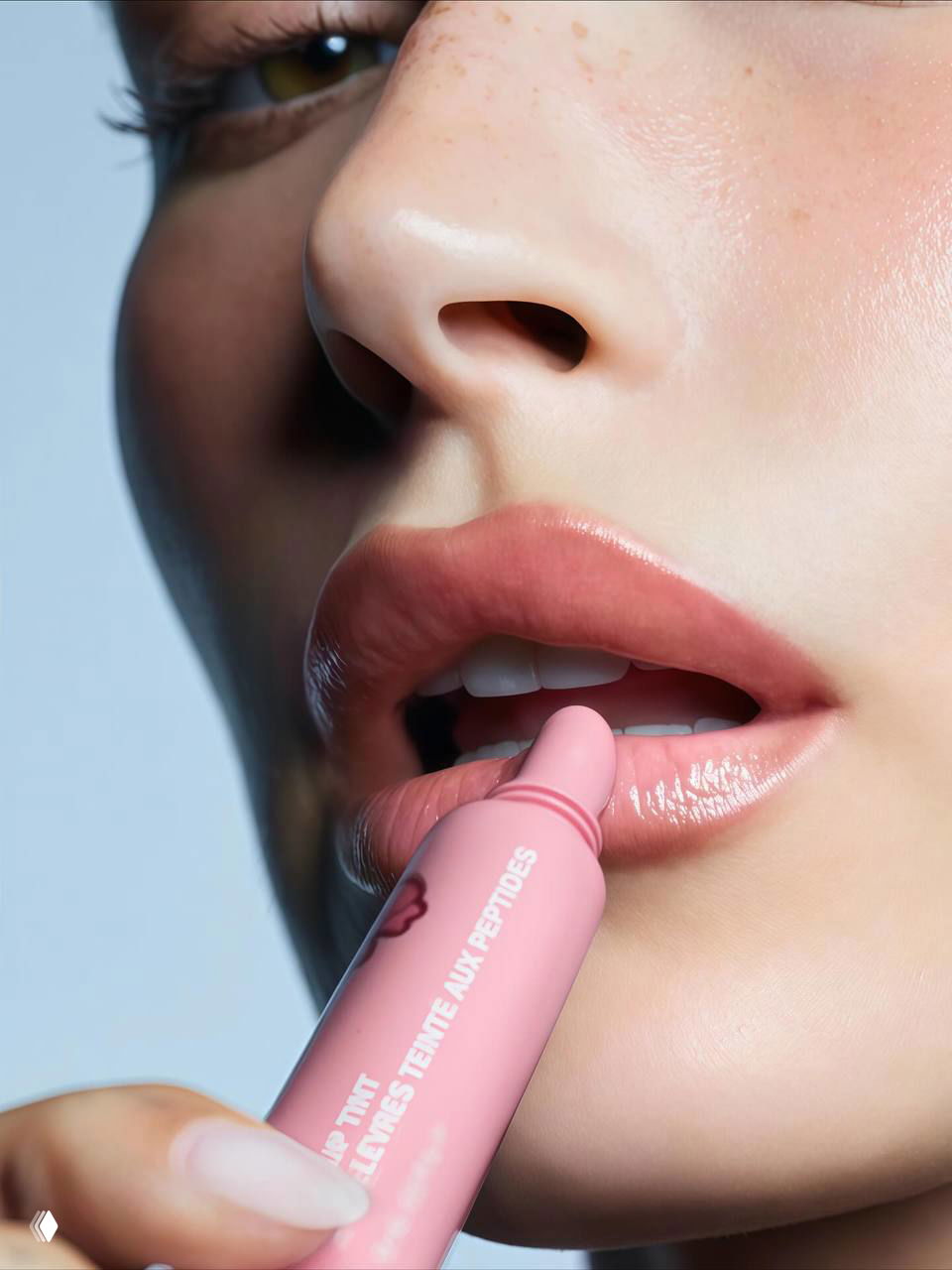 Крупный план губ модели, наносящей розовый тинт Rhode, демонстрирующий текстуру и оттенок продукта на губах.