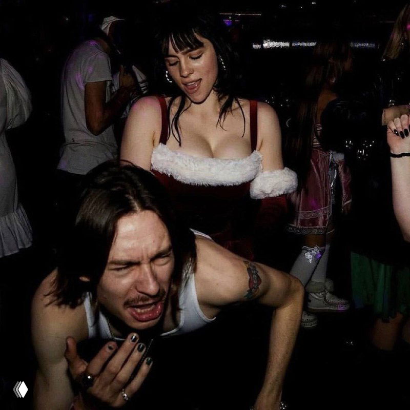 Энергичный кадр с вечеринки: Билли Айлиш в центре толпы, динамичный ракурс и тёмная клубная атмосфера с праздничными деталями.