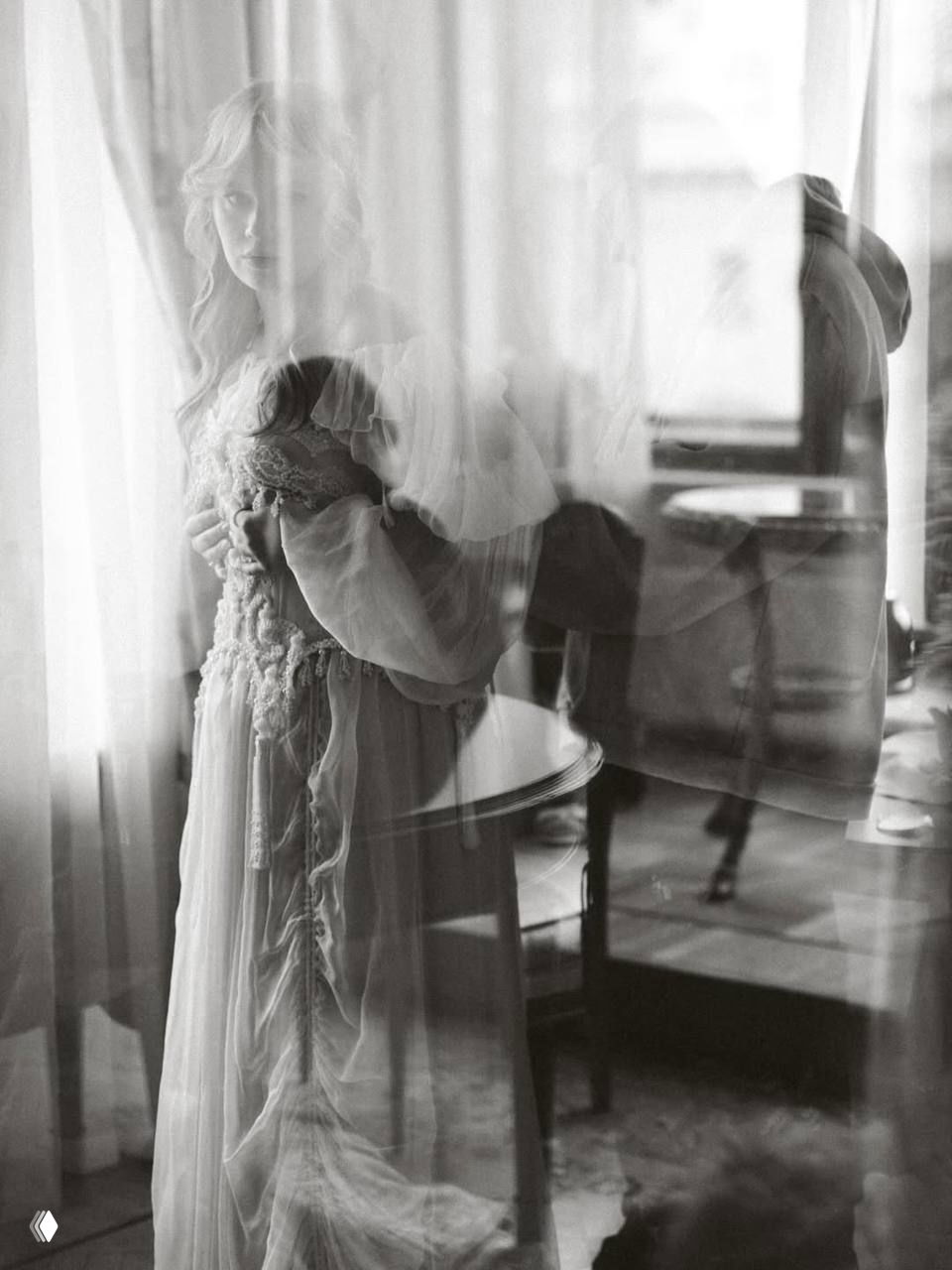 Чёрно‑белый художественный портрет невесты за прозрачной занавеской; сквозь ткань виден силуэт жениха, кадр в ретро-стиле.