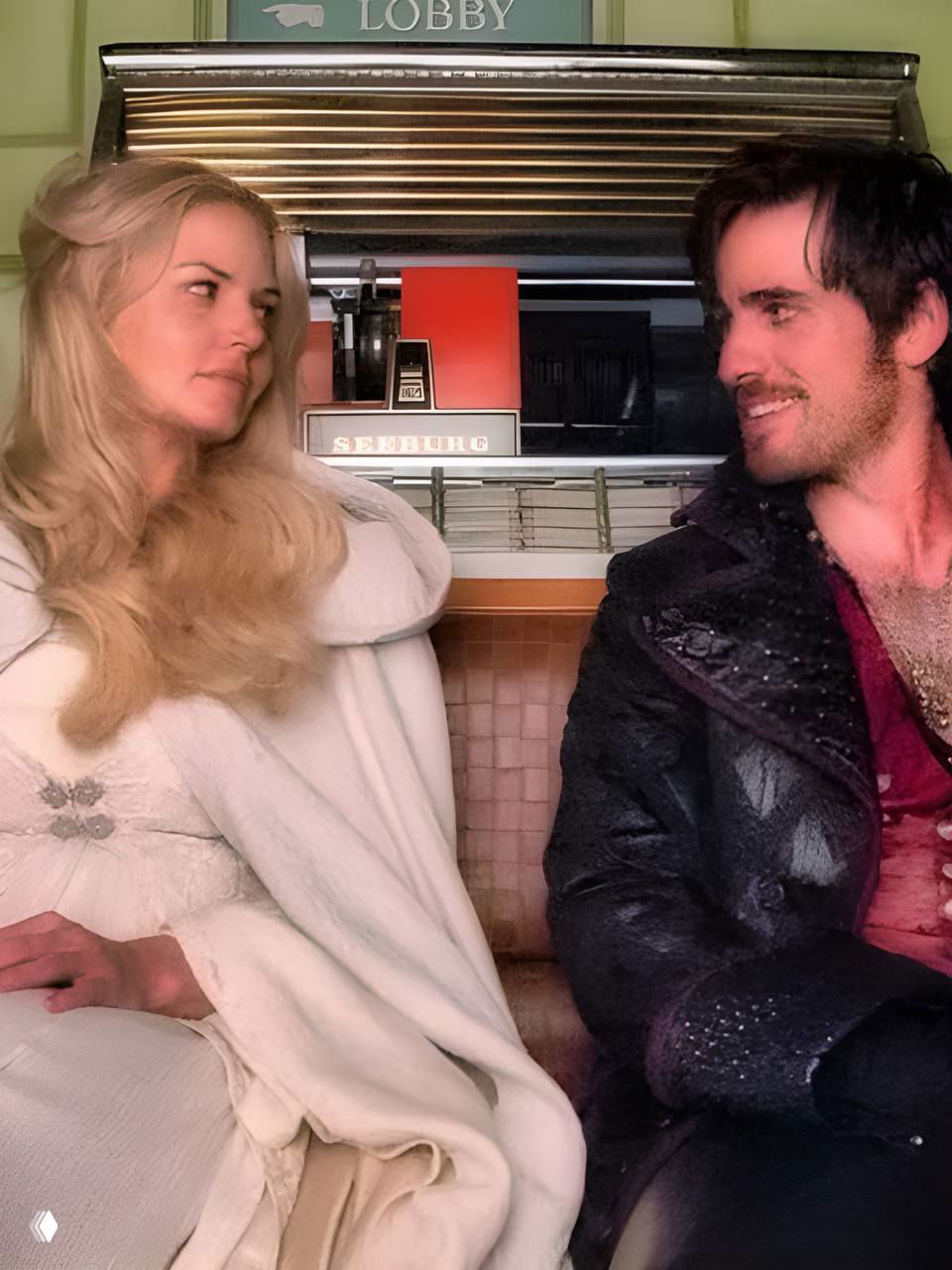 Два человека в костюмах сидят на скамье в интерьере площадки, между ними непринуждённый диалог и чашки кофе в руках.