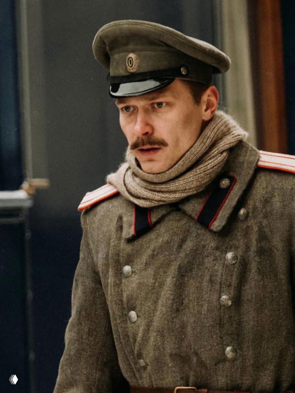 Кадр из исторического сериала: актёр в солдатской форме начала XX века на фоне зимней городской сцены, эмоциональный портрет персонажа.