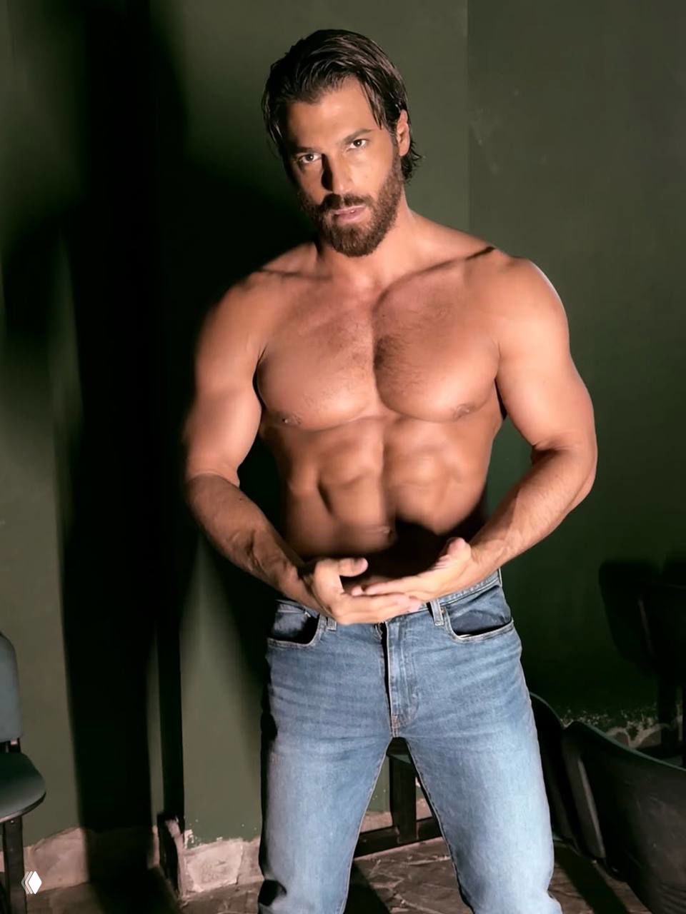 Портретный кадр Джана Ямана без рубашки: акцент на грудную клетку и пресс, актёр стоит в джинсах на тёмном фоне, серьёзное выражение лица.