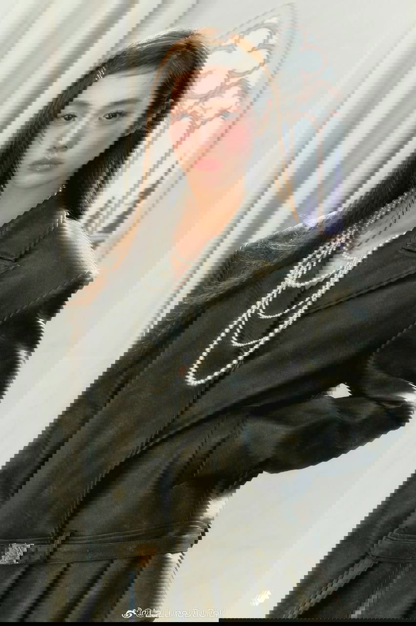 Фотомодель в пиджаке и жемчужных украшениях; ровные тёмные волосы с заколкой сбоку, акцент на ретро-образе.