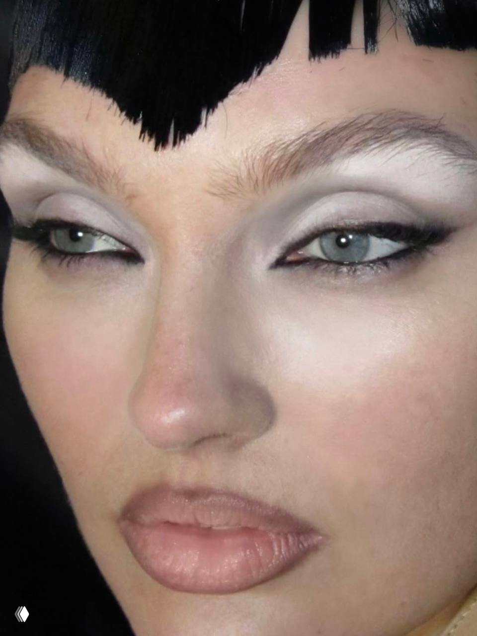 Деталь глаз и бровей с матовым светлым покрытием кожи и подчёркнутой стрелкой; образ цитирует бьюти‑тренды 90-х с современной подачей.