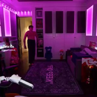 Кадр со стрима: фиолетовая комната, фигура без рубашки идёт по комнате; видны ковер, мебель и RGB-подсветка.