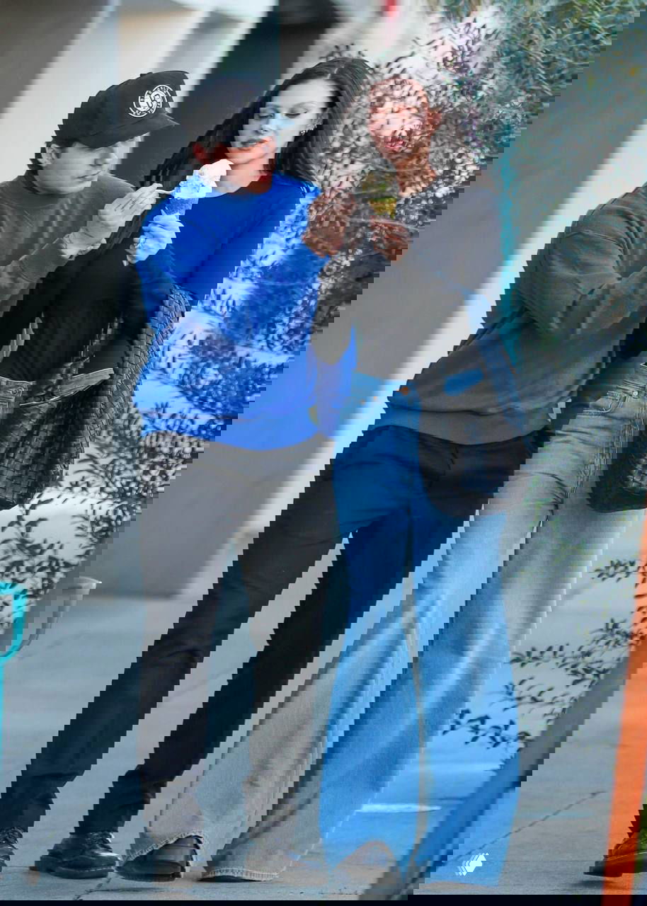 Бруклин Бекхэм и Никола Пельтц гуляют по улице: он в синем свитере и кепке, она в чёрном топе и широких джинсах, пара делит мороженое на ходу.