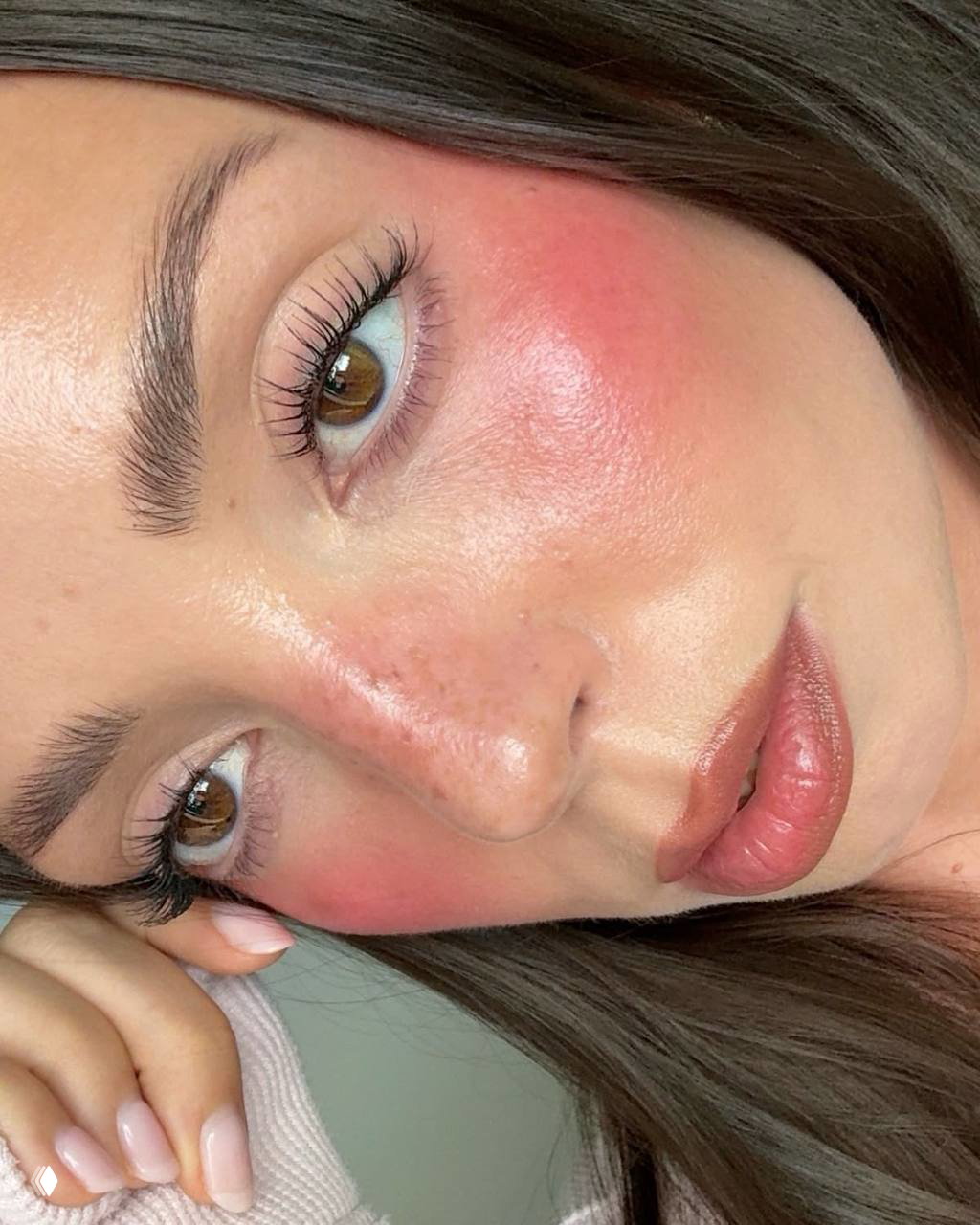 Крупный кадр лица под углом с интенсивными розовыми румянами на верхней части щёк и естественными ресницами.