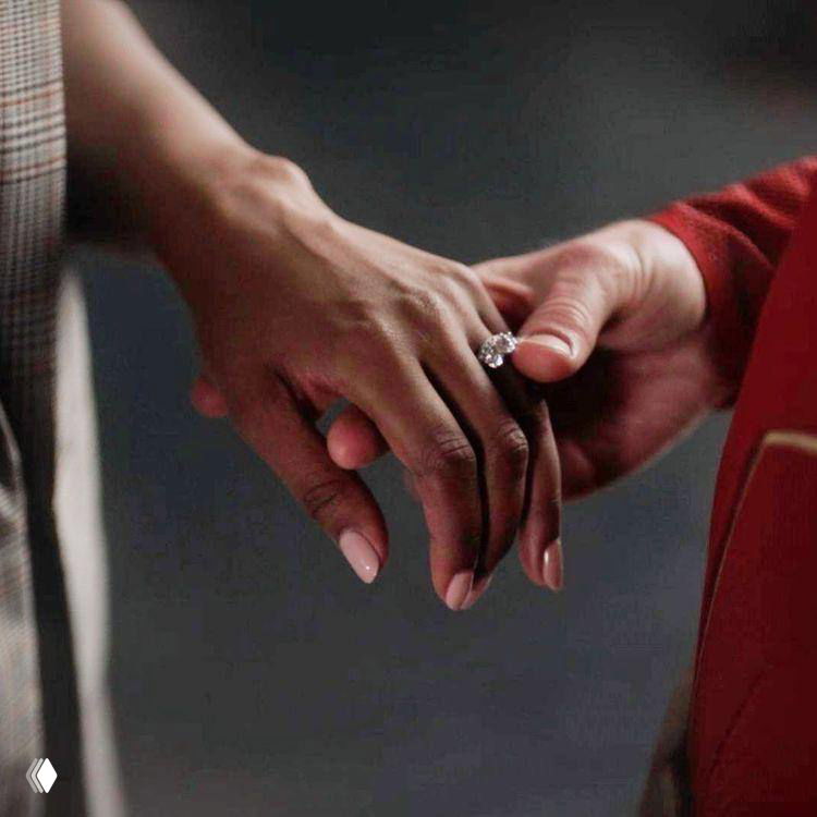 Крупный план рук пары: на пальце виднеется кольцо с крупным камнем — интимная сцена, близкий кадр эмоций.