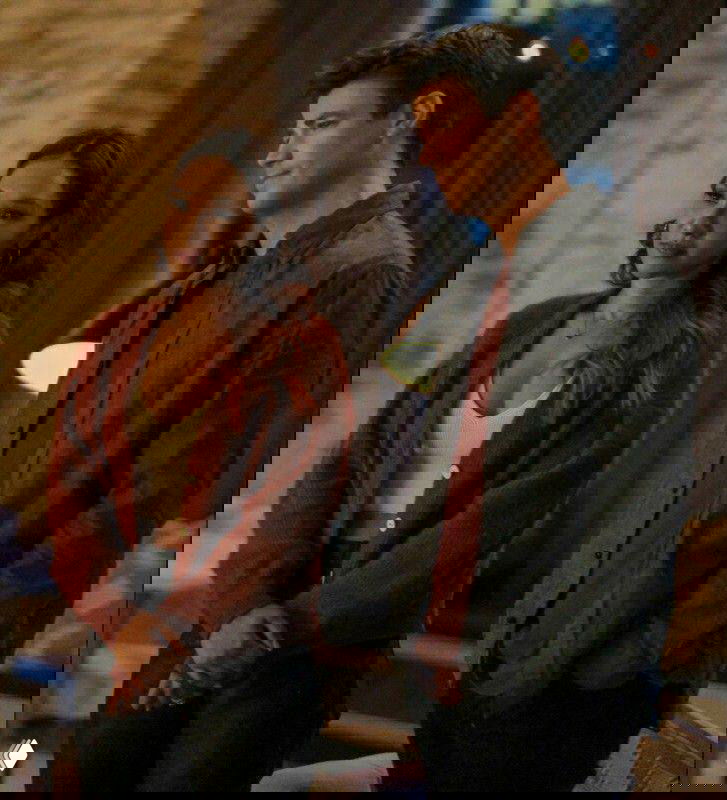 Сцена в интерьере: женщина в тёплом кардигане и мужчина в повседневной рубашке беседуют в помещении при мягком освещении.