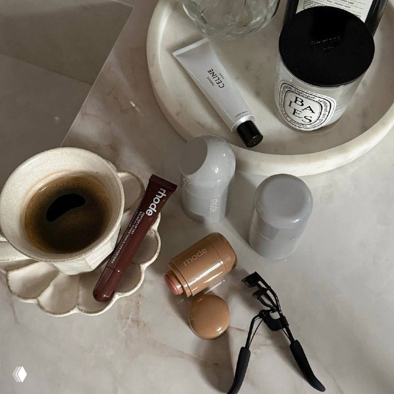 Искажённый и глитч-эффект на снимке: предметы на поверхности, бутылочка и аксессуары частично размыты и пикселизированы — художественный визуальный фрагмент.