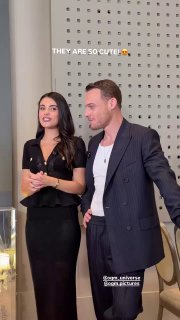 Кадр: Лизге Джемерт и Керем Бюрсин на мероприятии; акцент на чёрном платье с баской и золотыми пуговицами.