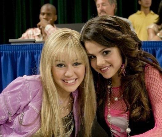 Кадр из молодёжного сериала: две молодые актрисы в костюмах героинь улыбаются в камеру на съёмочной площадке, тёплая сцена встречи.