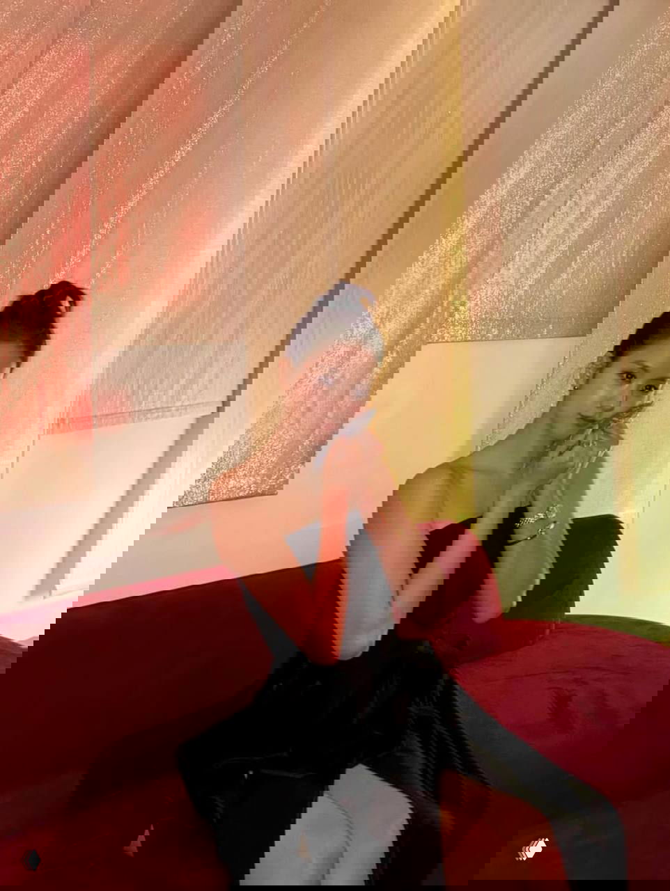 Джису в расслабленной позе на бархатном диване в чёрном платье, нежно прижимает платочек к щеке, аксессуары и браслет заметны на запястье.