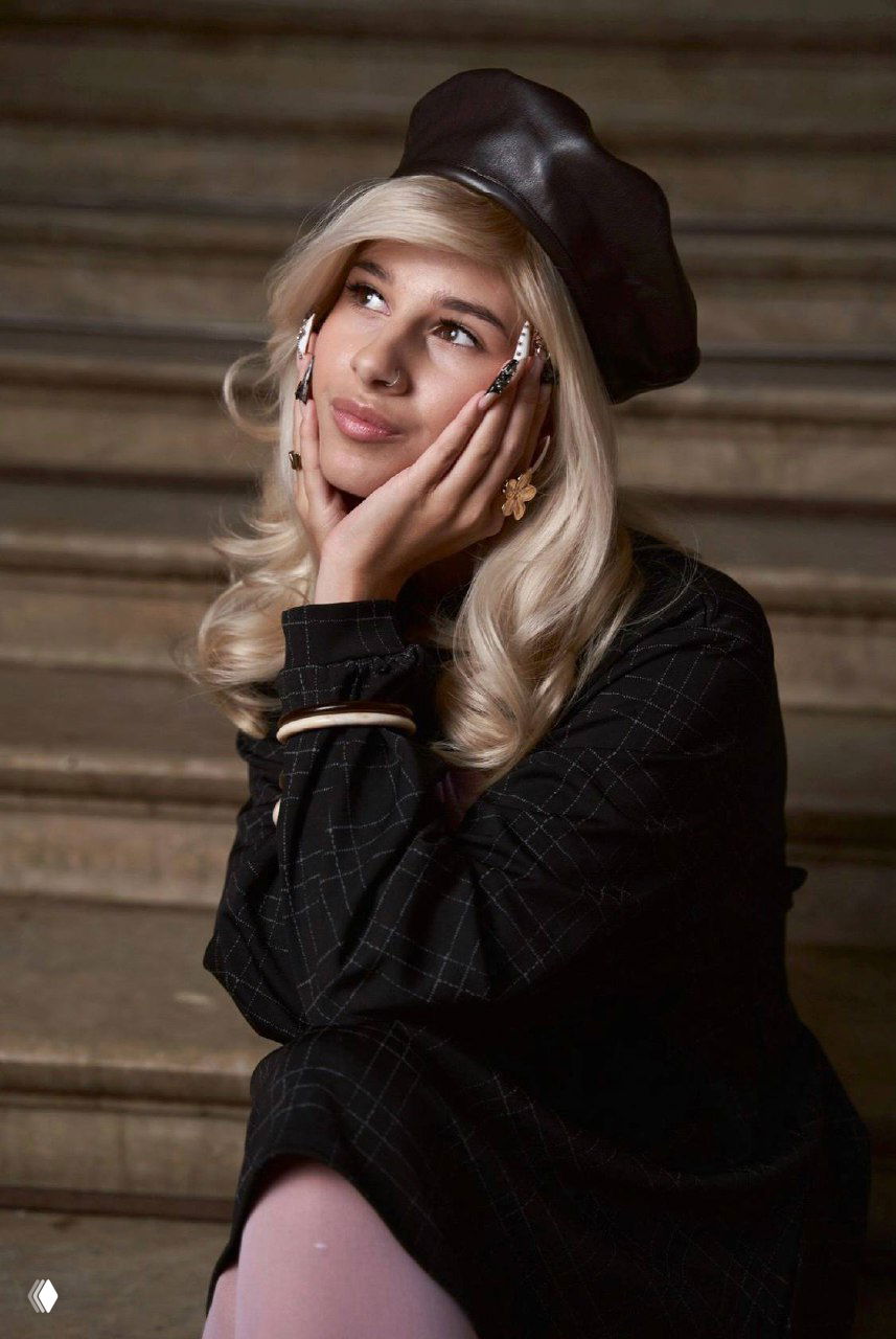 Портретный кадр StesOK в тёмном наряде и беретe: классический «Gossip Girl» стиль и выразительная поза на уличной локации.