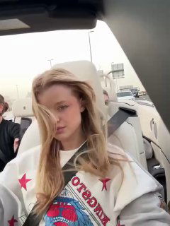 Портрет Кристи Крайм в салоне автомобиля с лёгким причёском, мягким светом и городским фоном через окно, кадр из поездки по Дубаю.