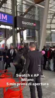Большая толпа у входа в магазин Swatch в торговом центре: множество людей выстраиваются в очередь рядом с витриной и логотипом Swatch.