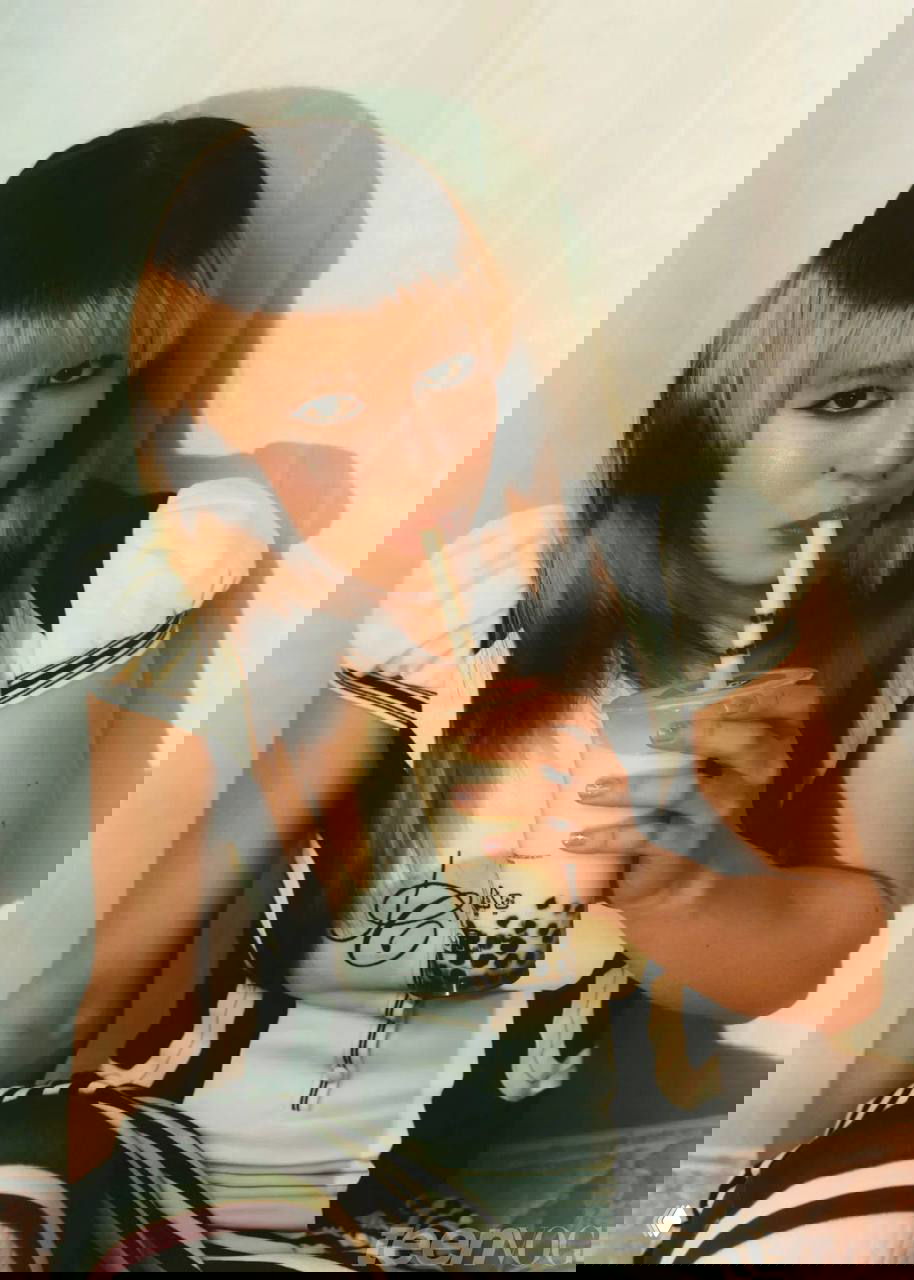 Алиса Лью в ретро-образе пьёт напиток через трубочку (bubble tea), расслабленная поза и стилизация в кадре для Teen Vogue.