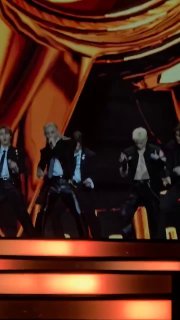 Члены Stray Kids во время номера на французском благотворительном вечере, сценический свет, синхронные движения и эффектный фон