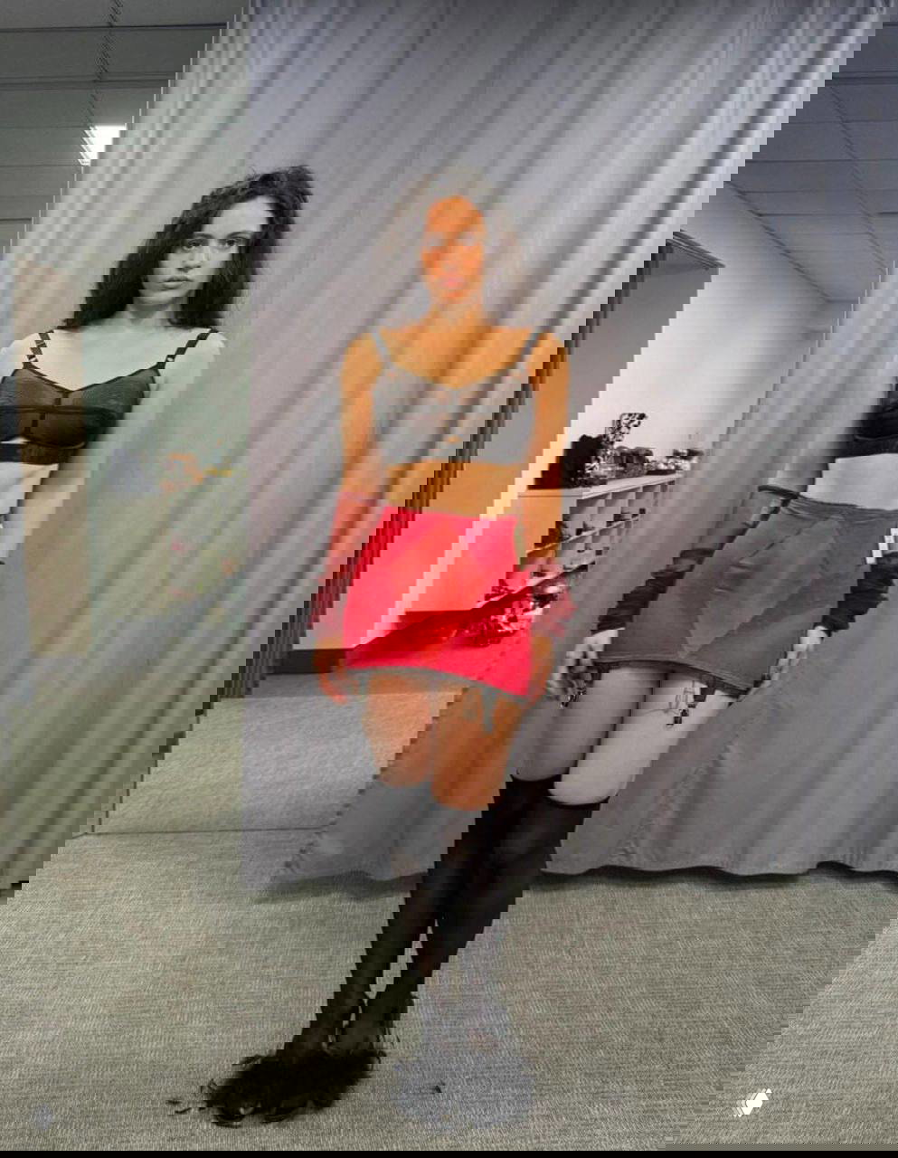 Полный рост актрисы в ярком сценическом костюме: корсет, мини-юбка и чулки в примерочной или гримёрной зоне съёмочной базы