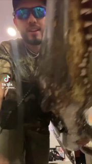 Мужчина в камуфляже и солнцезащитных очках держит крупного аллигатора в руках — кадр из видеоролика с мужским образом супруга Ланы Дель Рей.