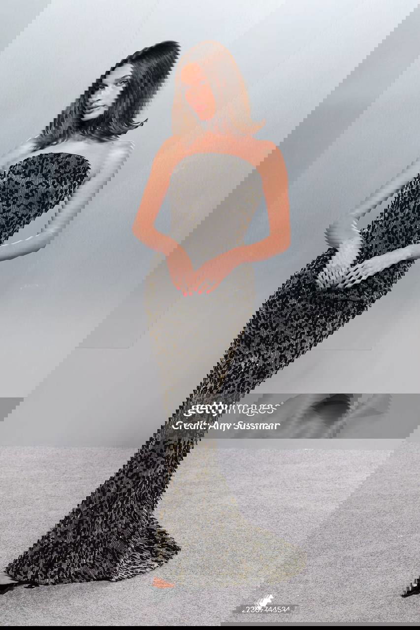 Женщина в облегающем платье с леопардовым принтом и элегантным силуэтом позирует на серая фоне фотозоны афтепати.