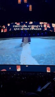 Кадр с панельной сессии Disney: сцена со светящимися фонариками и проекцией заголовка «FIRST LOOK AT DISNEY'S LIVE ACTION TANGLED» на большом экране.