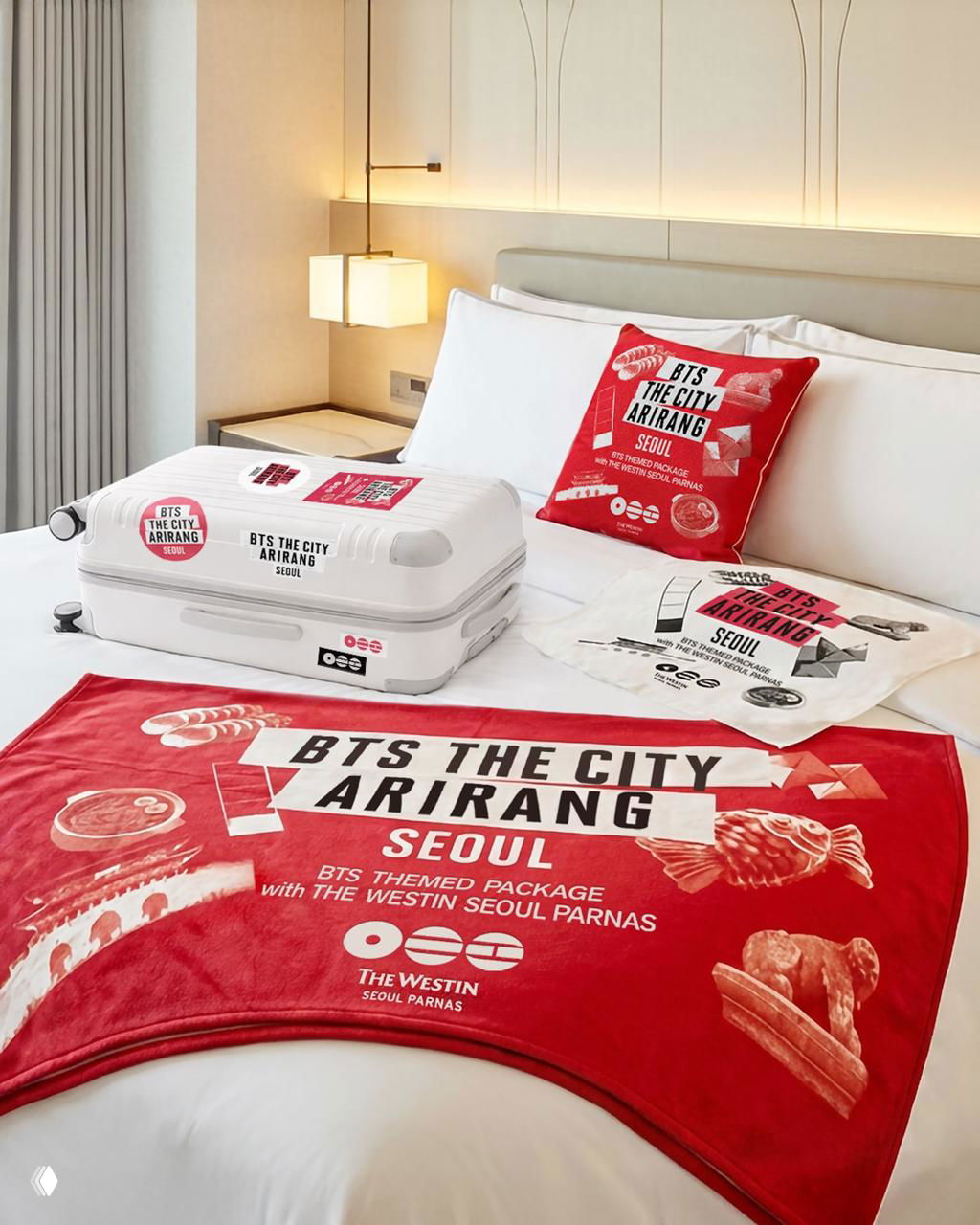 Комната отеля с тематическими пледами, подушками и багажом в оформлении «BTS THE CITY ARIRANG SEOUL» — коллаборация с гостиницей.