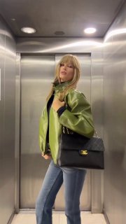 Кадр из ролика: блогерка в яркой зелёной кожаной куртке и джинсах позирует в лифте с сумкой Chanel — смелый модный весенний look.