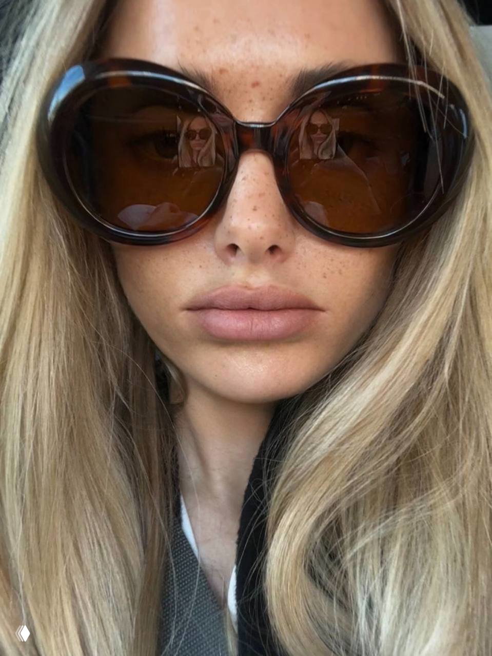 Крупный портрет с эффектными круглыми очками oversize и веснушчатым лицом: тёплый коричневый оттенок линз, естественный дневной свет и спокойный взгляд.