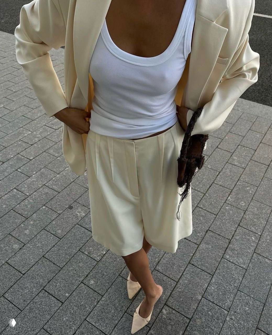 Крупный план бежевого костюма с бермудами и белым топом, сочетание брючного костюма и летней майки в элегантном городском образе