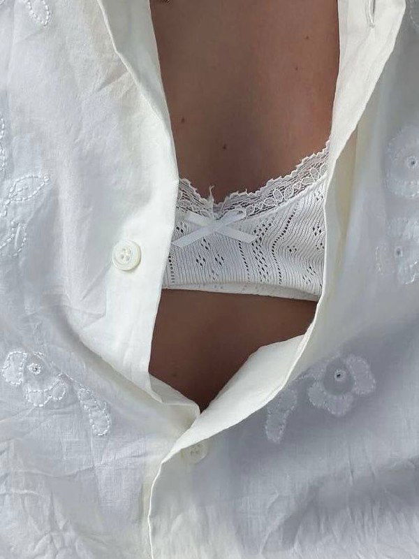 Фрагмент белого кружевного платья и участок кожи под тонкой тканью; изображение частично искажено пикселизацией, акцент на текстурах и кружевах.