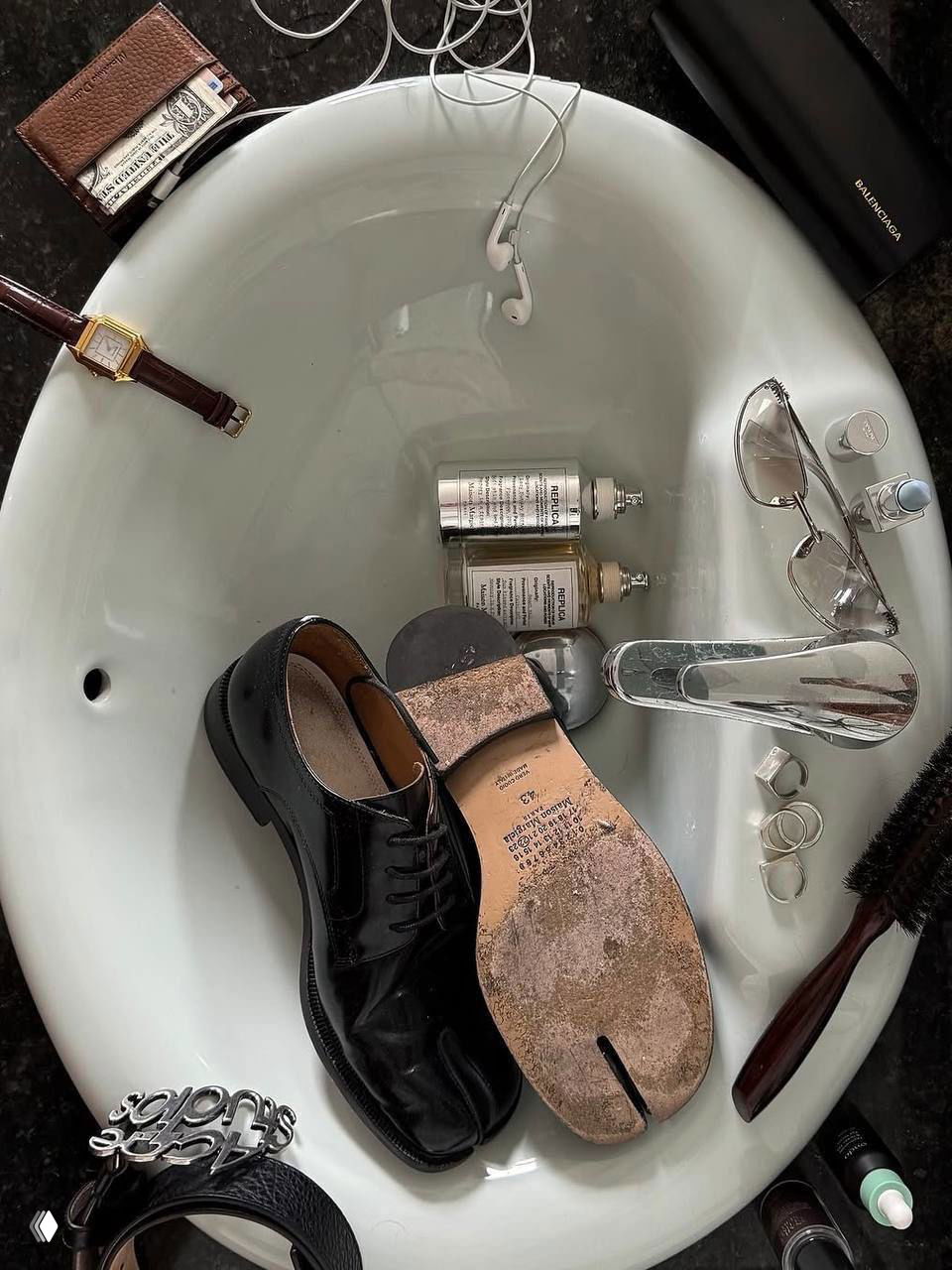 Набор аксессуаров в раковине: чёрные дерби, таби‑подошва, очки, флаконы парфюма и украшения — детали для moodboard эстетики.